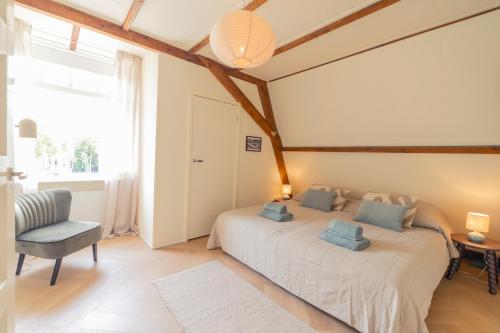 a bedroom with a bed and a chair and a window at Luxury Family Apartment with canal & Peperbus view in Zwolle