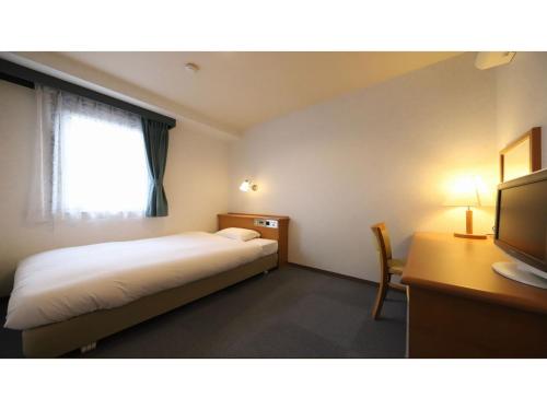 a bedroom with a bed and a desk and a television at Smile Hotel Takaoka Ekimae - Vacation STAY 89658v in Takaoka