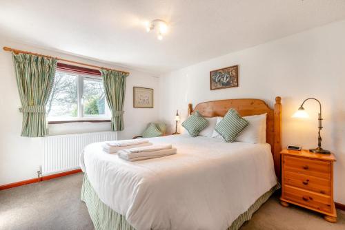 a bedroom with a large white bed and a window at Wren Cottage in St Merryn