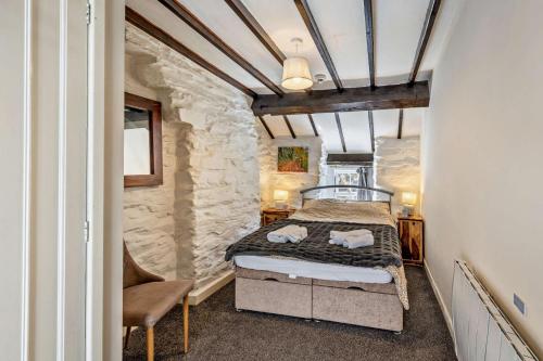 a bedroom with a bed and a chair in a room at Cascades Cottage in Blaenau-Ffestiniog