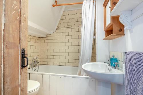 a bathroom with a tub and a sink and a toilet at West Creek Cottage in Little Petherick