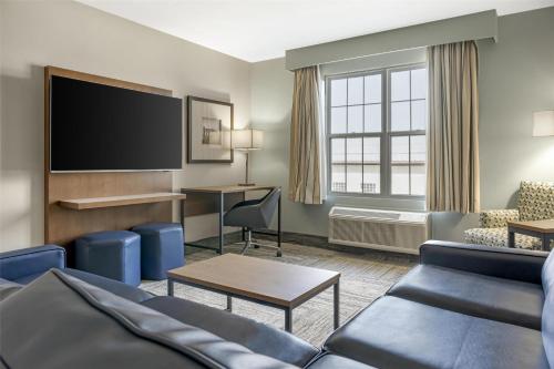 a living room with a couch and a flat screen tv at Best Western Plus Woodstock Hotel Conference Centre in Woodstock