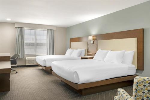 a hotel room with two beds and a desk at Best Western Plus Woodstock Hotel Conference Centre in Woodstock