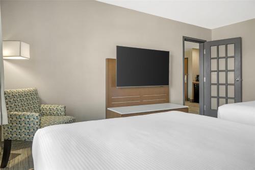 a bedroom with a bed and a tv and a chair at Best Western Plus Woodstock Hotel Conference Centre in Woodstock