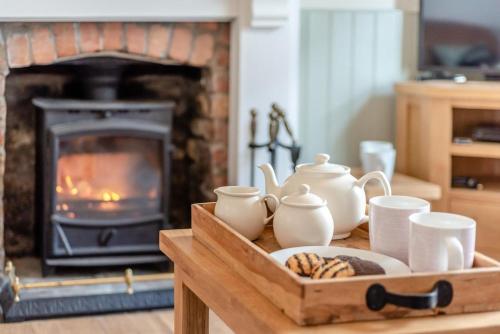 a table with a tray with cups and a fireplace at Wellies in Appledore
