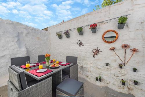 a patio with a table and chairs and a wall at Wellies in Appledore