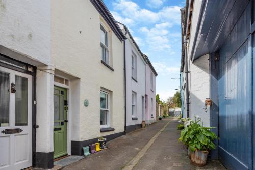 an alley with white buildings and a green door at Wellies in Appledore
