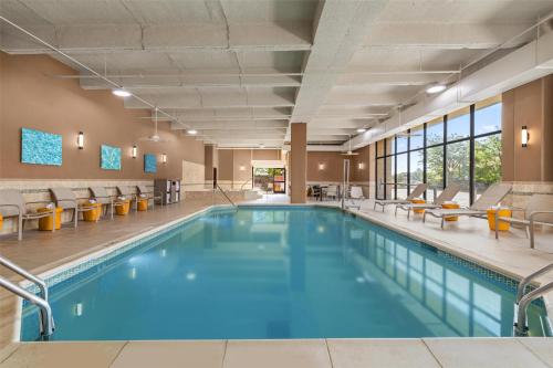 a swimming pool with chairs and tables at Drury Plaza Hotel St Louis Creve Coeur in Creve Coeur
