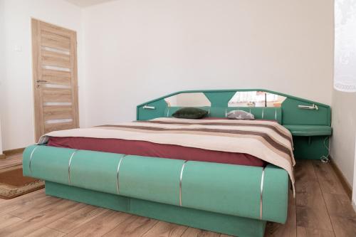 1 cama con marco verde en un dormitorio en Apartmán pri Belej, en Pribylina