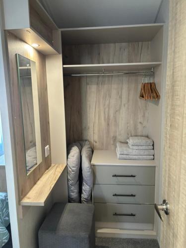 a walk in closet with a white dresser and a mirror at Seafront Serenity Lodge in Newbiggin-by-the-Sea