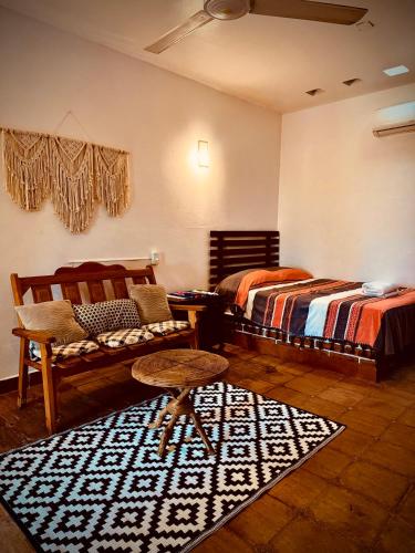 a bedroom with two beds and a chair and a rug at Casa Terranova in Puerto Escondido