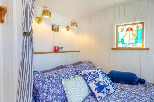 a bedroom with blue and white pillows and a window at Plas Uchaf Farm Retreat in Llannefydd
