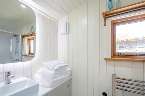 a white bathroom with a sink and a mirror at Plas Uchaf Farm Retreat in Llannefydd