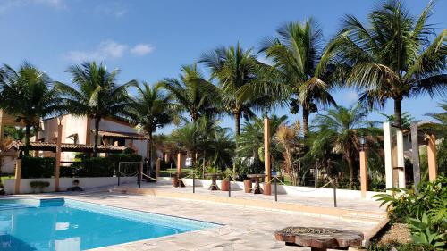a swimming pool with palm trees in front of a building at Pousada Atelier Aly da Costa in Iguape