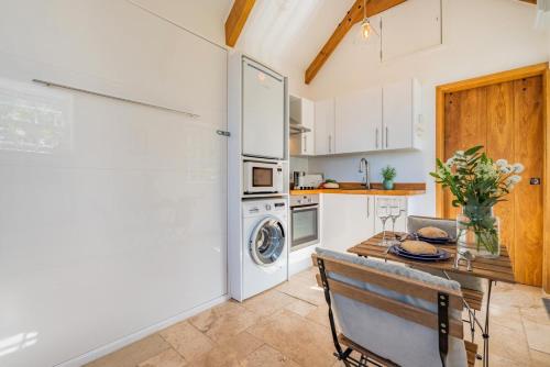 a kitchen with a table and a washer and dryer at The Studio at the Old Vicarage in Pendeen