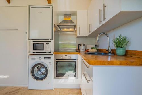 a kitchen with a washing machine and a sink at The Studio at the Old Vicarage in Pendeen