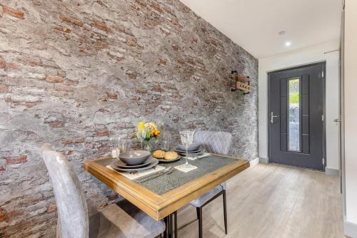 a dining room with a table and a brick wall at Aderyn Du in Berriew