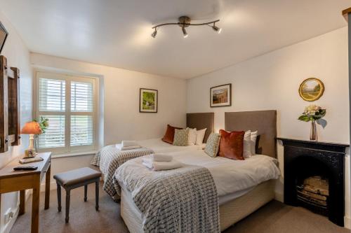 1 dormitorio con 2 camas y chimenea en Low Dog Kennel, en Cartmel
