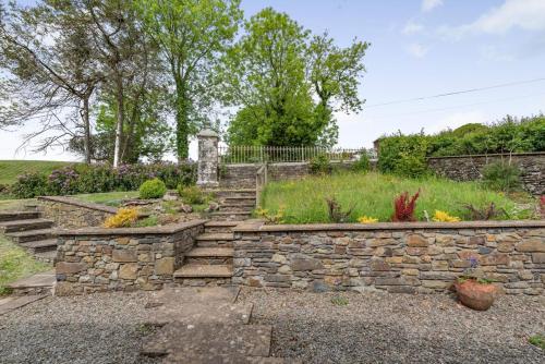 a stone retaining wall with stairs in a garden at The Gate Lodge Brynteg in Llanwenog
