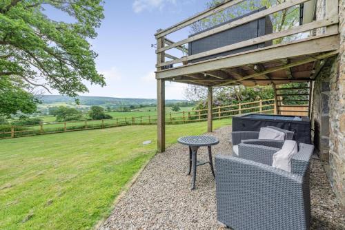 a patio with a table and a chair under a pergola at The Gate Lodge Brynteg in Llanwenog