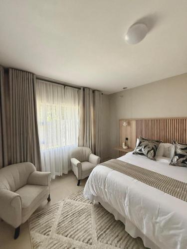 a bedroom with a bed and a chair and a window at PEREZ Apartments - ELEGANT LIVING IN THE LUSH GREENDALE SURBUB in Harare