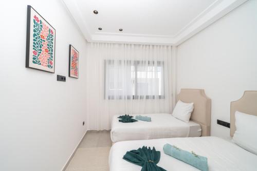 two beds in a room with white walls at LUXURY Apartment - IPTV - AC - Easy Parking - Cosy stay in Tangier