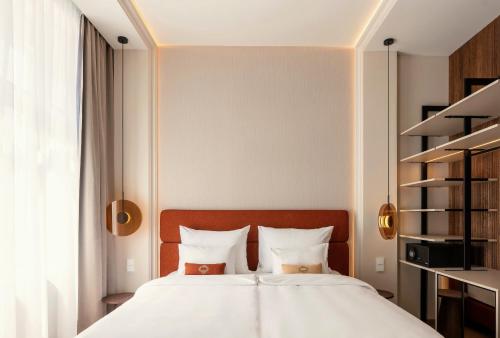 a bedroom with a white bed with two pillows at LOVIS Suites Vienna in Vienna