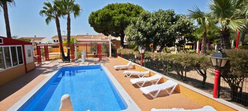 een zwembad met witte ligstoelen naast een resort bij Finca los Barrancos in Lepe