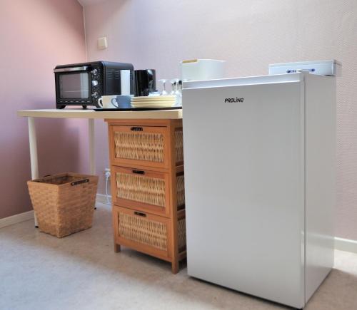 a refrigerator next to a table with a microwave at Suite familiale avec 2 Chambres dans une villa - quartier vert et boisé - 5 kms de Namur in Namur