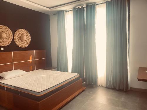 a bedroom with a bed and a window with curtains at COMFORT INN-Executive apartments in Bujumbura