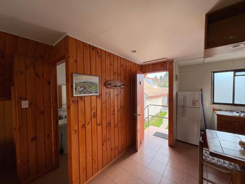 a kitchen with wooden walls and a refrigerator and a door at Cabañas Villa Alejandra in Las Cabras