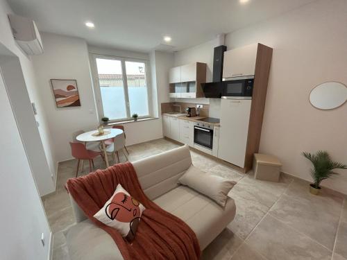 ein Wohnzimmer mit einer weißen Couch und einer Küche in der Unterkunft Bel appart moderne et climatisé "PAUL" in Alès