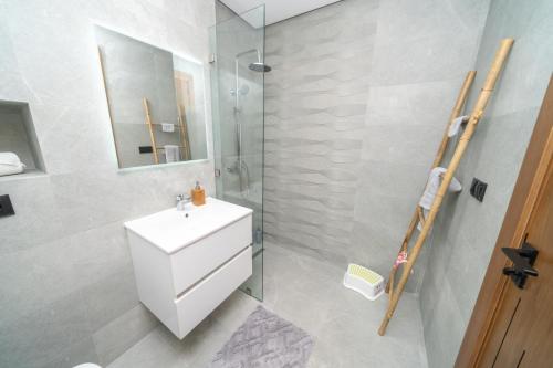 a bathroom with a white sink and a shower at LUXURY Apartment - IPTV - AC - Easy Parking - Cosy stay in Tangier