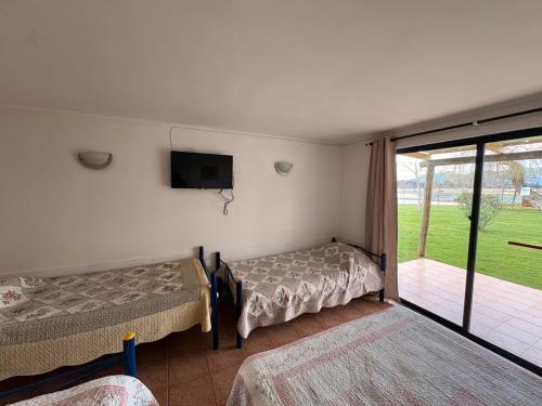 a bedroom with two beds and a tv and a balcony at Cabañas Villa Alejandra in Las Cabras