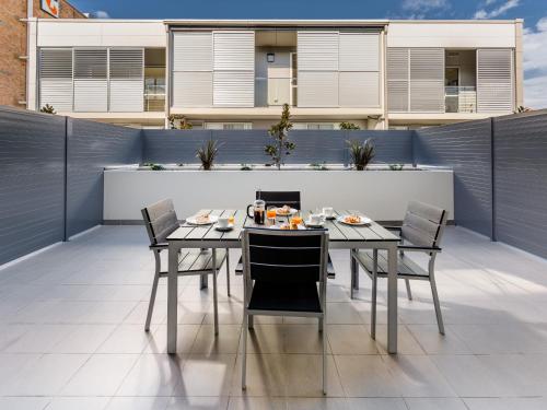 Une table à manger et des chaises sont disponibles sur la terrasse. dans l'établissement Hamilton Executive Apartments, à Newcastle