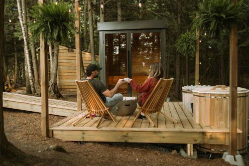 two people sitting in chairs on a wooden deck at Aux Box Muskoka Modern Muskoka Bunkie in Huntsville