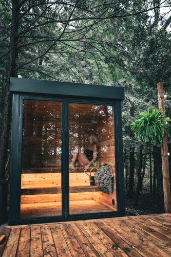 a screened in porch on a deck with a woman sitting in it at Aux Box Muskoka Modern Muskoka Bunkie in Huntsville