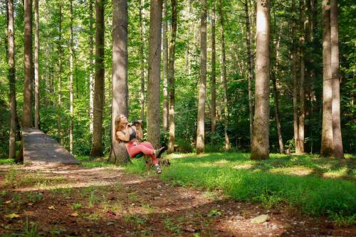 a woman sitting on a bench taking a picture in the woods at Summer Breeze cabin at Cabin Fever in NC in Saluda