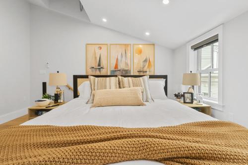 a white bedroom with a large bed with two lamps at North End Entire House in Boston