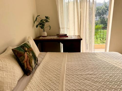 a bedroom with a bed with a window and a table at Amber- Sun-Kissed Holidays, Goa in Chicalim