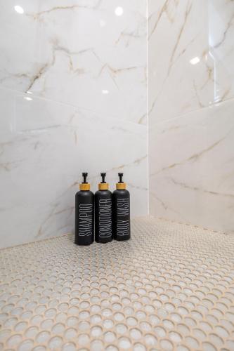two black shampoo bottles sitting on a white tiled bathroom at North End Entire House in Boston