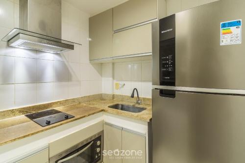 a kitchen with a sink and a stainless steel refrigerator at Apto 1 Quarto em Cond. Frente Mar MNDA0217 in Škorak