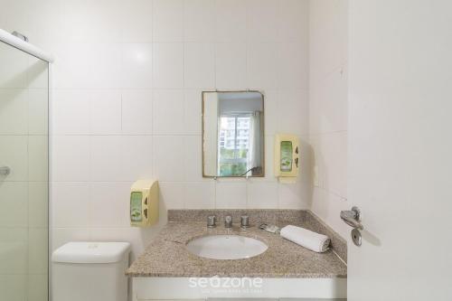 a bathroom with a sink and a mirror and a toilet at Apto 1 Quarto em Cond. Frente Mar MNDA0217 in Škorak
