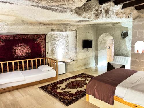 a bedroom with two beds and a tv in a room at My Cave Suites in Nevsehir