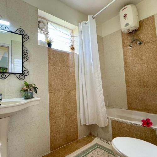 a bathroom with a toilet and a sink and a tub at Amber- Sun-Kissed Holidays, Goa in Chicalim