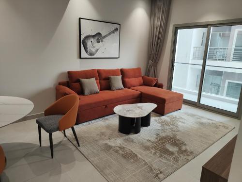 a living room with a red couch and a table at Muscat City Stay-2BR Apt 108 near Grand & Avenue Mall in Ghubrah