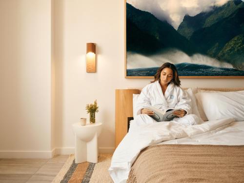 a woman sitting on a bed reading a book at Flow Brickell Hotel in Miami