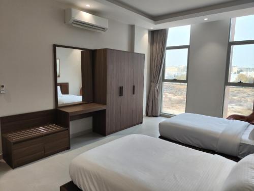 a hotel room with two beds and a mirror at Muscat City Stay-2BR Apt 108 near Grand & Avenue Mall in Ghubrah