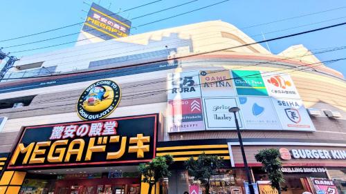 a building with signs on the side of it at MIYAVI#302 3min walk Narimasu Station, 4 people, wide queen bed & sofa, Tokyo's largest Don Quijote in Tokyo