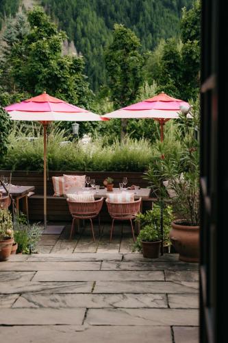 a patio with tables and umbrellas in a garden at Strasserwirt - Ansitz zu Tirol in Strassen